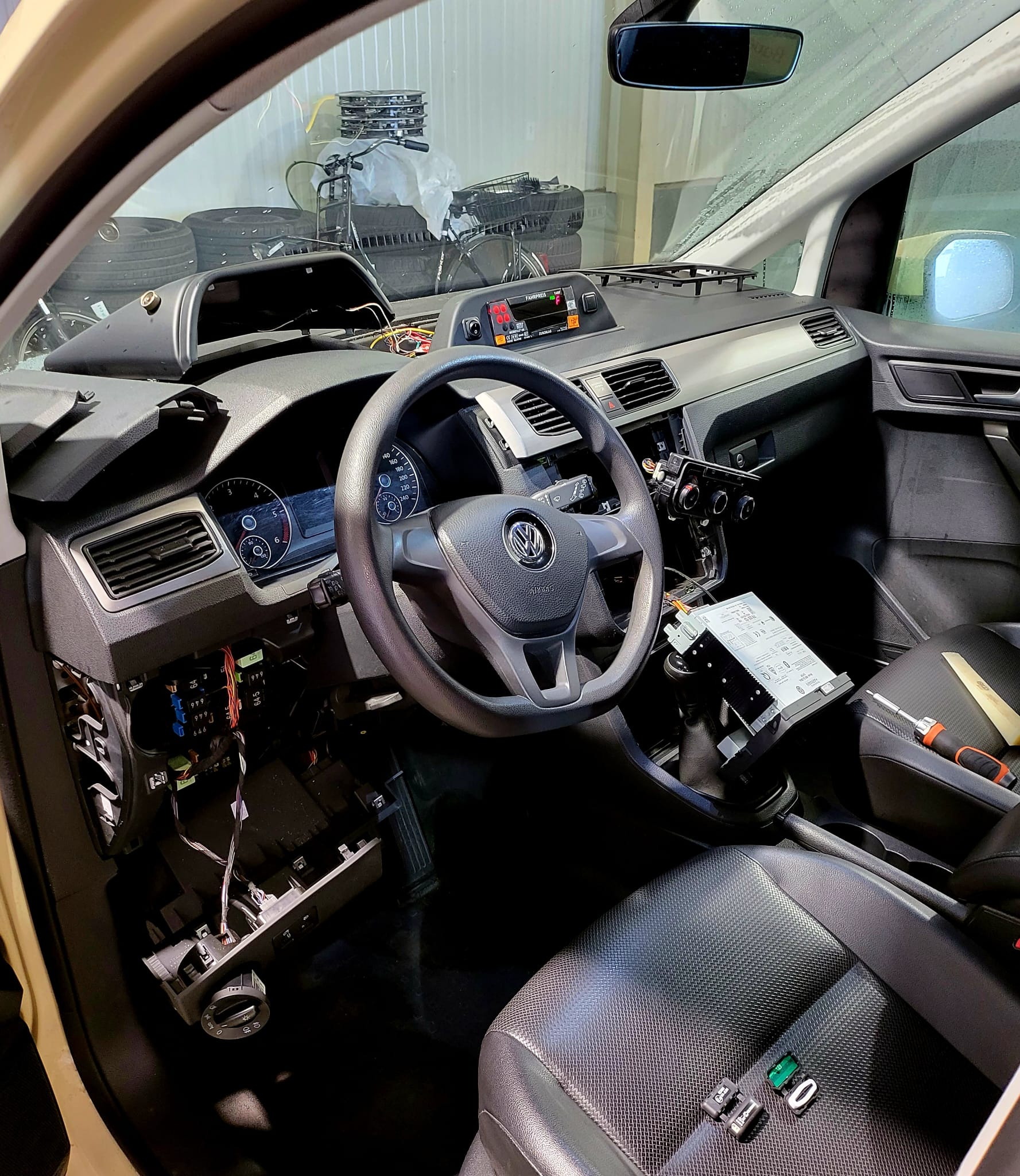 Das geöffnete Armaturenbrett eines Autos zeigt den Einbau von Fahrzeugortungstechnologie mit verschiedenen Werkzeugen.