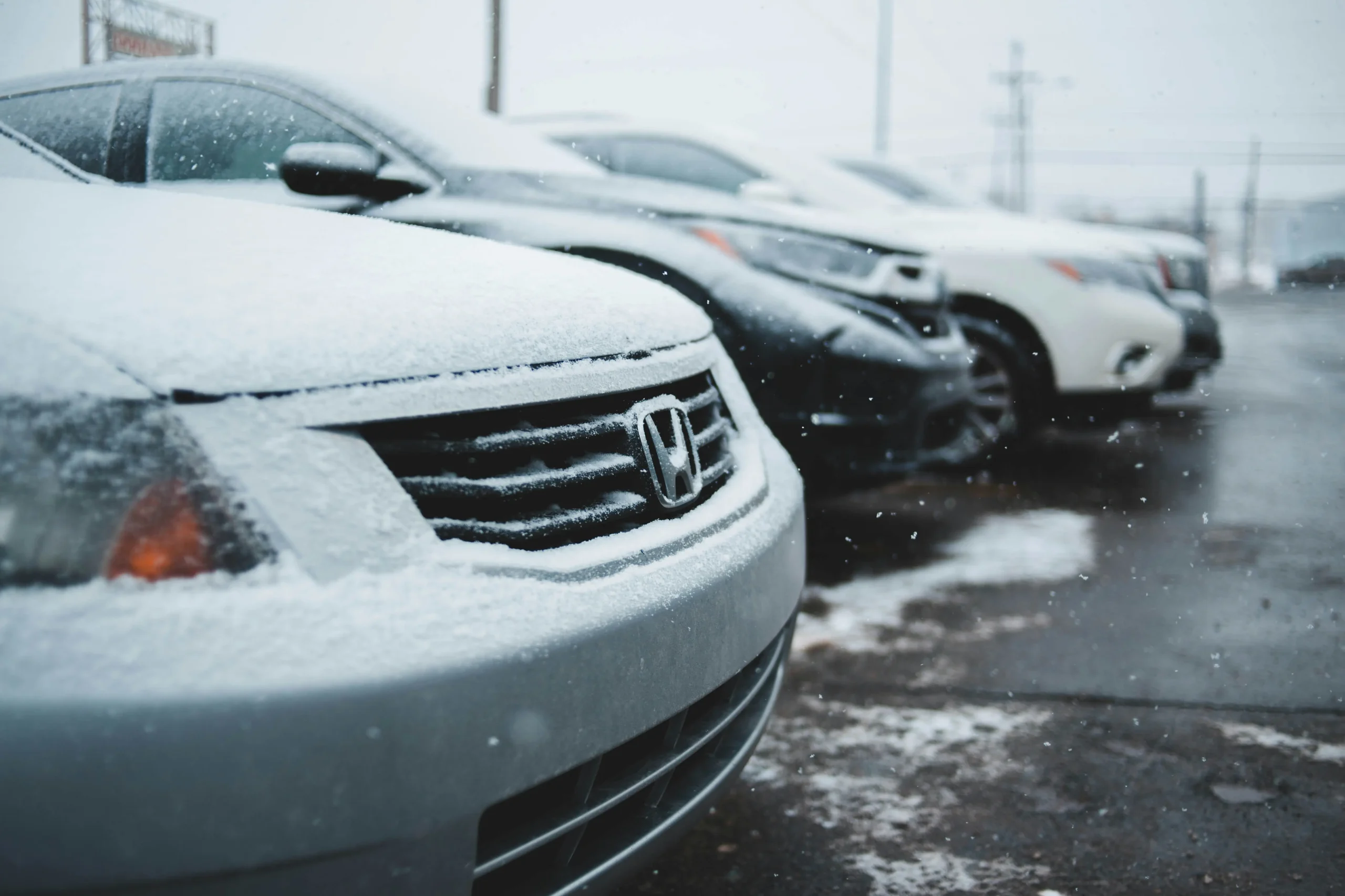 Eine Reihe verschneiter Autos steht auf einem Parkplatz, ideal für GPS Ortungslösungen bei winterlichen Bedingungen.