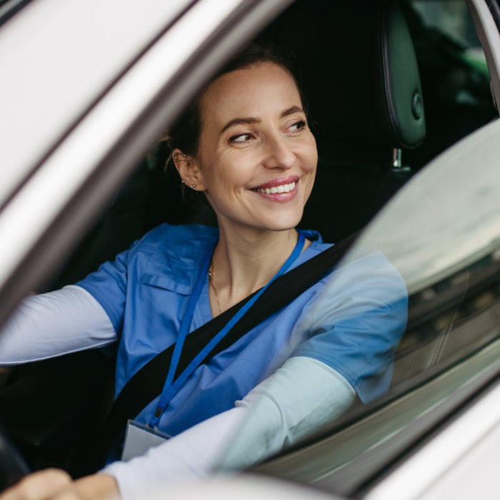 Eine lächelnde Frau im Auto schaut aus dem Fenster, während sie GPS Ortung für effiziente Fahrzeugortung nutzt.
