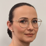 Eine Frau mit Brille blickt selbstbewusst in die Kamera, während sie über GPS Ortung und Ortungslösungen informiert.